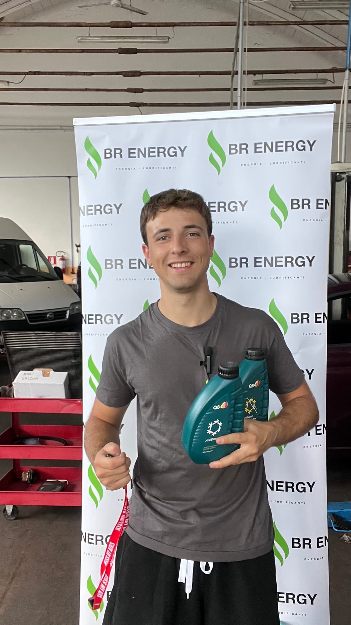Nicolò Bianchi con due taniche di lubrificante davanti a un banner BR Energy