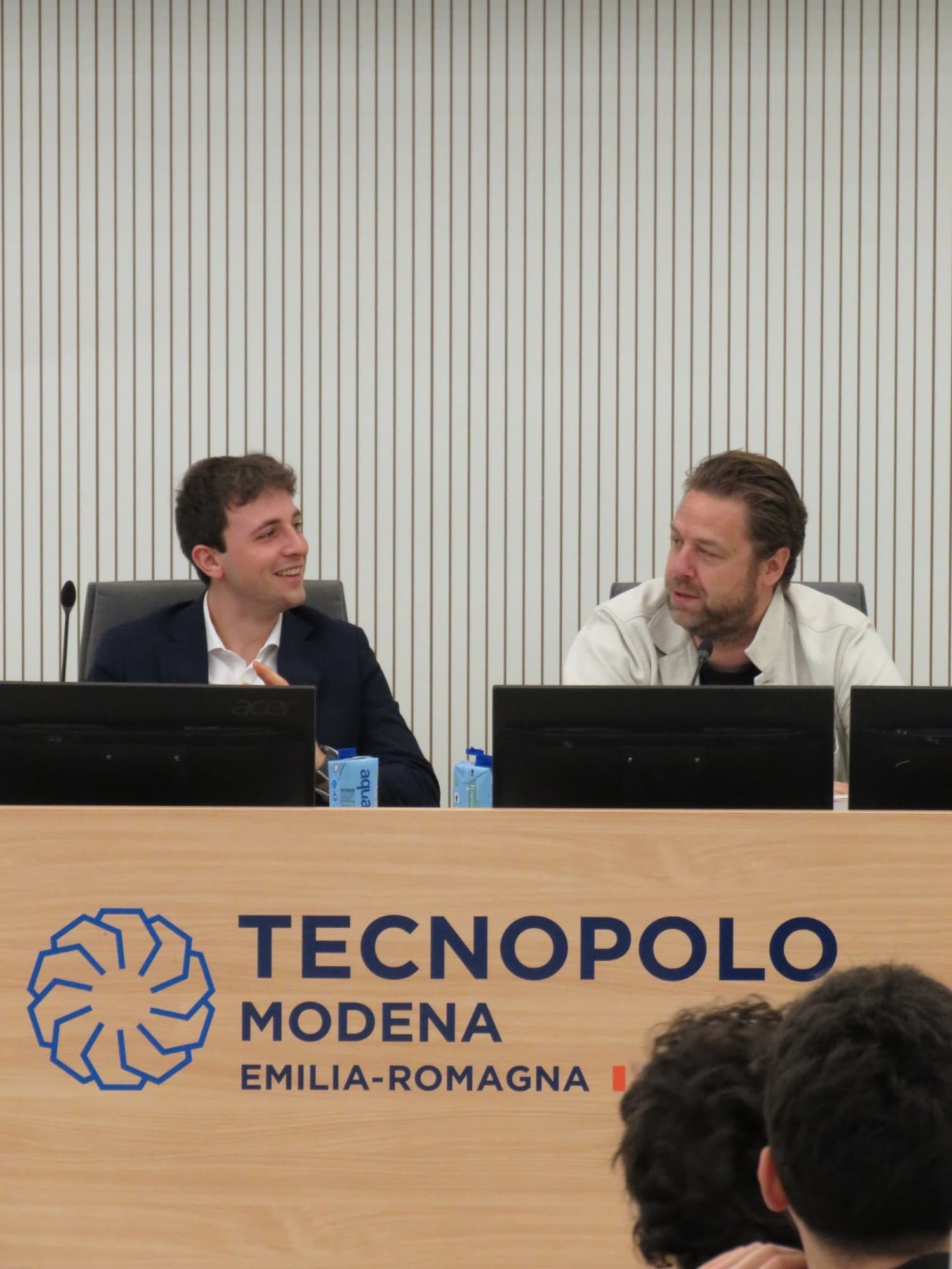 Due relatori seduti al tavolo del Tecnopolo di Modena durante un incontro